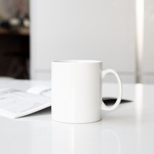 a white coffee cup sitting on top of a white table